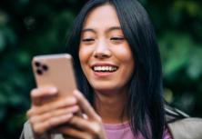 woman outside smiling looking at smartphone